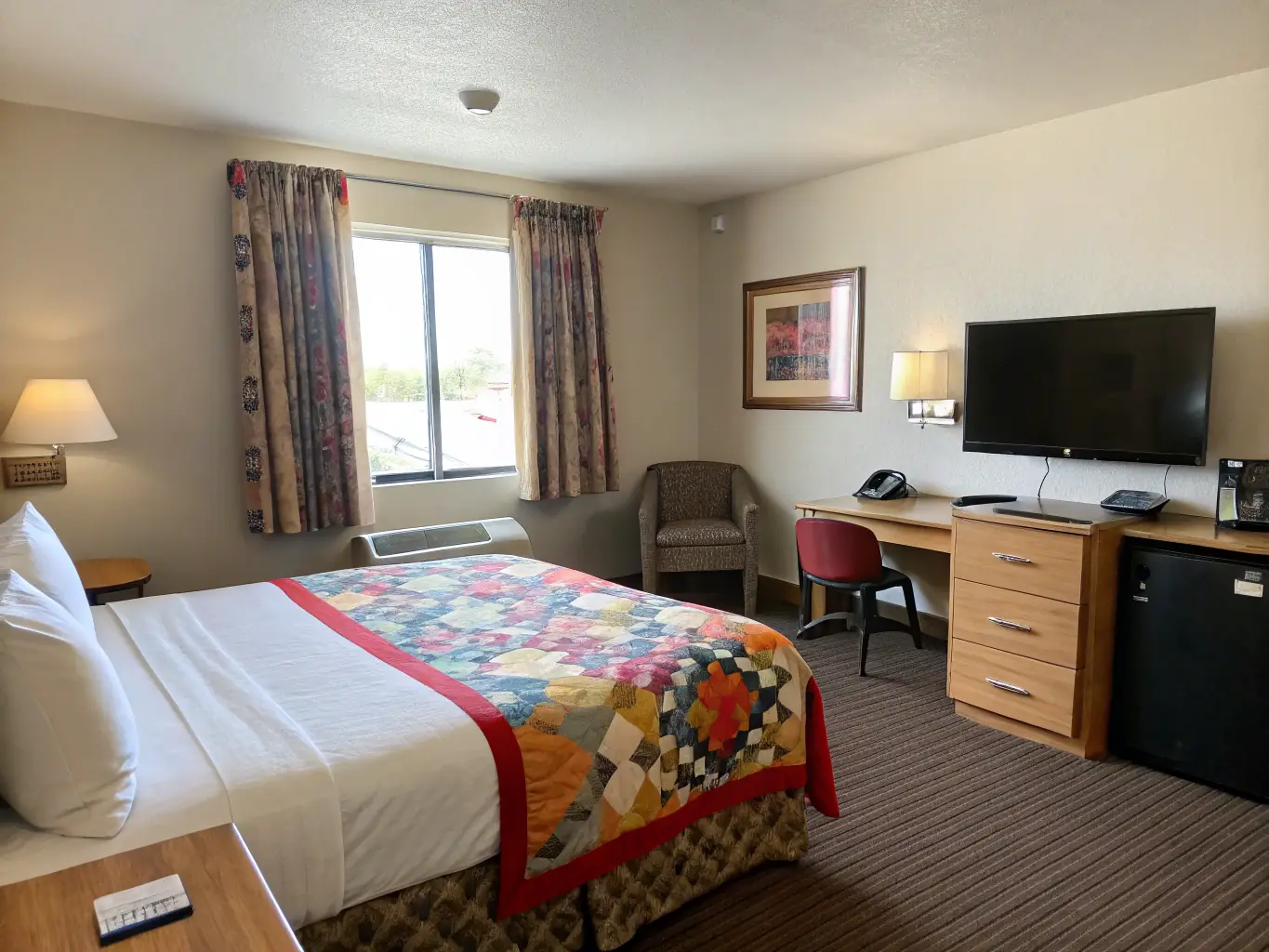 A brightly lit, well-maintained Economy room at Olymp Hotel, featuring a comfortable bed, a small desk, and essential amenities, conveying a sense of practicality and value.